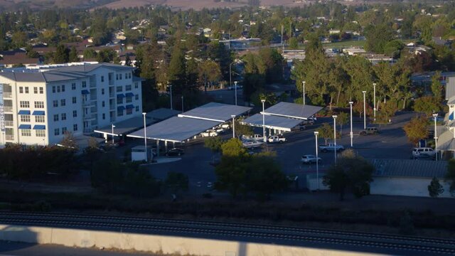 Aerial view over cars on a highway, towards apartments with solar carport shelter panels - tilt, drone shot