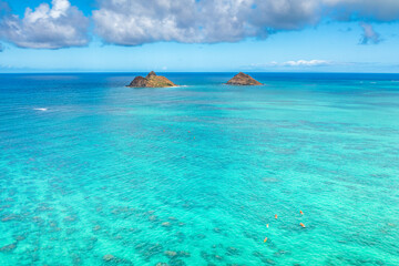 Fototapeta premium Aerial drone view of the Mokolua islands off the coast of Lanikai Beach in Oahu, Hawaii, USA. Water is turquoise, reef is visible, few white clouds in sky. 