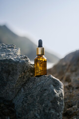 A bottle of serum on stones on a sea background.