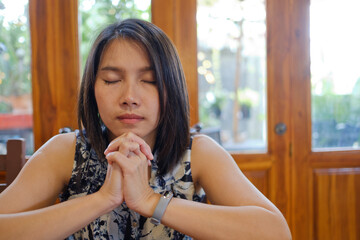 Woman praying, hands folded in prayer
