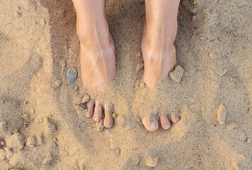 Relax on the beach with feets in the dry and hot sand on the beach. Selective focus. Shot from above.