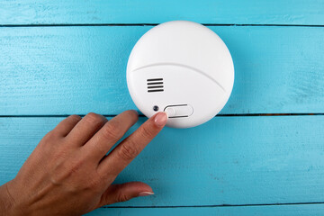 Smoke detector. Woman's finger presses the test button. Smoke, fire alarm
