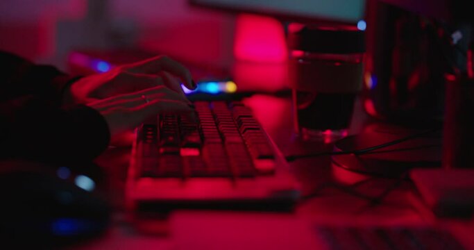 computer hacker typing on keyboard hacking data on internet cyber crime information hack by anonymous hacker using rgb gaming keyboard with red backlight