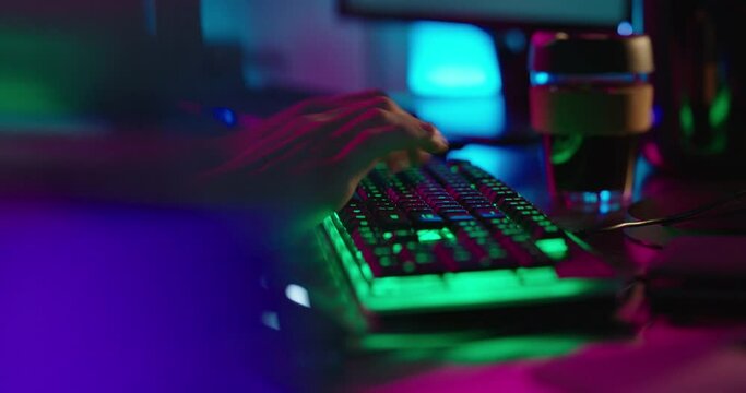 computer hands typing on keyboard hacking data on internet cyber crime information hack by anonymous hacker using rgb gaming keyboard with green backlight