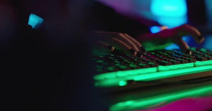 computer hands typing on keyboard hacking data on internet cyber crime information hack by anonymous hacker using rgb gaming keyboard with green backlight