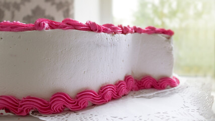 Obraz na płótnie Canvas Pink cream on a white cake. Side view. The concept of home baking, making cakes