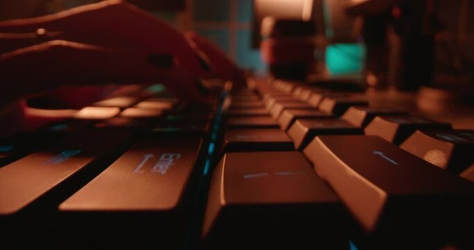 macro hands typing on keyboard computer programmer coding software using keyboard with blue backlight anonymous person hacking at night