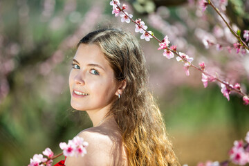 Naklejka premium Portrait of happy girl in red dress in a blooming spring garden
