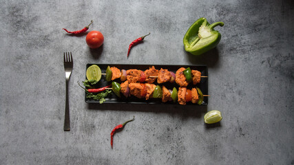 Chicken kebabs or doners grilled with saute vegetables on a black tray. Top view.
