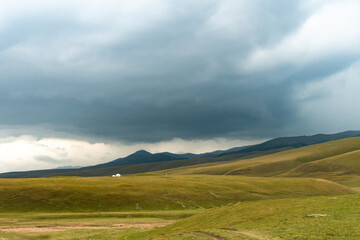 Endless steppe in the valley at the foot of the mountains, bathed in bright sunlight. Amazing view on  green mountains. mountain, covered with green trees, under a blue sky with clouds.