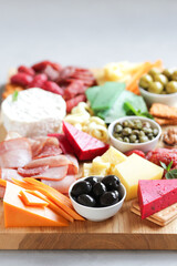 Large wooden board for snacks with different cheeses, meats, sausages, olives, nuts. Nice serving board with meats and cheeses. Vertical on a light background.
Close-up