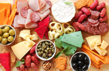 Charcuterie boards. Assorted meat, sausages, cheeses with nuts, olives, croutons on a wooden board. Food on a wooden background. View from above. 