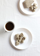 Cup of natural coffee.
Halva dessert in plates on a white background.
Copy of space, top view