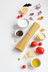 Naklejka na ściany i meble Food ingredients for Italian pasta, spaghetti, fresh farm tomatoes, garlic, peppers, basil, olive oil, Parmesan cheese, lemon, vegetable milk. On white background. Top view with copy space.