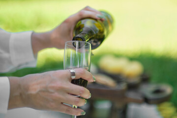 Wine pouring from bottle, outdoor picnic. concept of female alcoholism.
