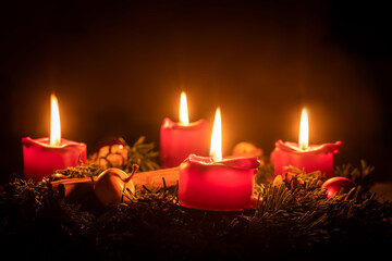 Decorated advent wreath made of fir branches with burning red candles