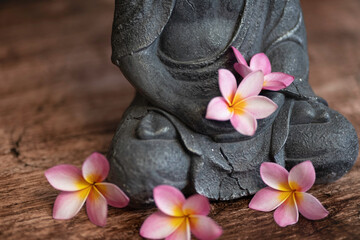 Buddha statue with frangipani flowers on a dark background
