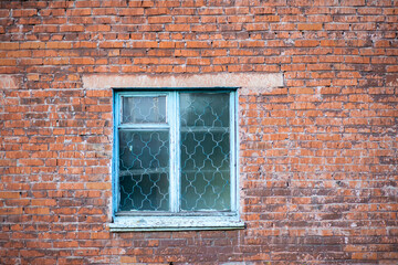 Old shabby wall facade of a brick building with wooden glass windows in turquoise color. The concept of poverty, corruption and destruction. High quality photo