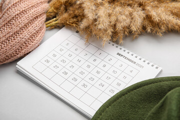 Calendar with hat, scarf and pampas grass on light background, closeup