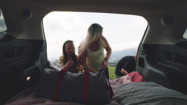Mother and kids packing bags into trunk