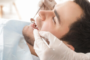 Dentist examining teeth of young man in clinic