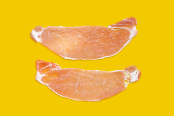 Sliced raw pork meat on yellow background.