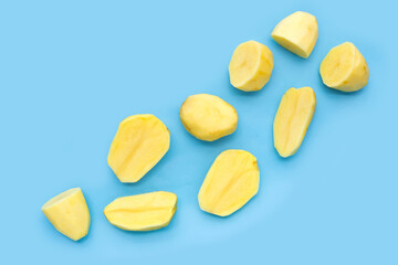 Raw peeled potatoes on blue background