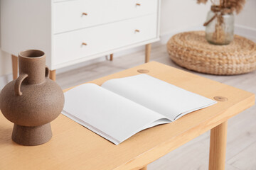 Vase with open magazine on table in room