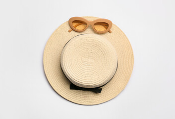 Stylish hat and sunglasses on white background