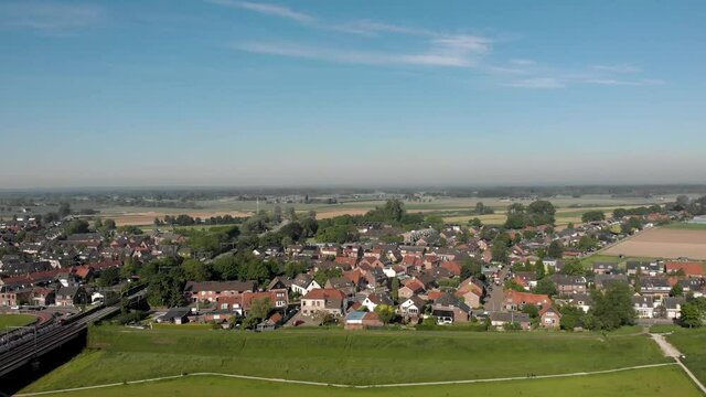 Aerial cityscape of De Hoven across river IJssel in Zutphen, The Netherlands, against a blue sky with floodplains in the foreground.