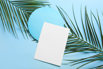 Composition with blank cards and palm leaves on color background