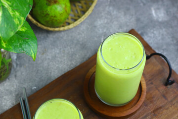 Jus Alpukat or Avocado juice served with clear glass and cut of avocado fruits. 