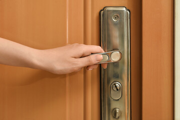 Woman opening door in room, closeup