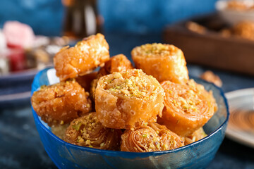 Bowl with delicious baklava on color background, closeup