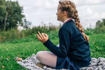 School girl meditating outdoors. Mental health awareness at school concept.
