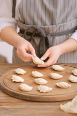 Obraz na płótnie Canvas Woman preparing tasty dumplings on kitchen table, closeup