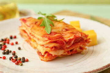 Plate with piece of tasty tomato lasagna on table, closeup