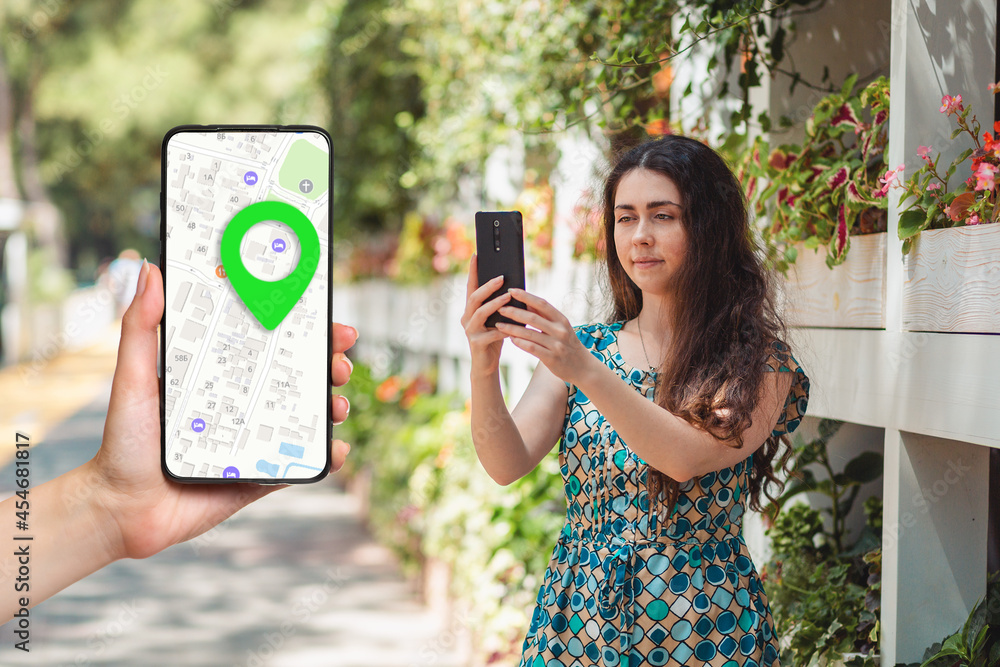 Wall mural a females hand holds a smartphone with an online map app and a marked destination. in the background