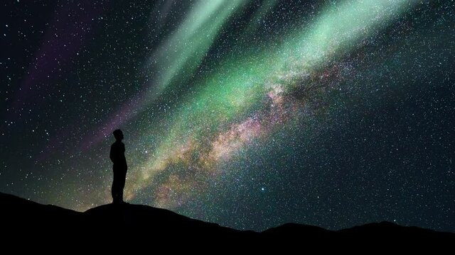 The man stand on a starry sky background with a polar light. time lapse