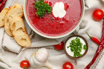 Composition with tasty borscht on light fabric background, closeup