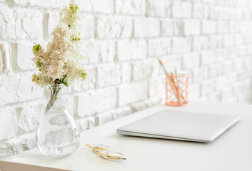 Modern workplace with laptop near brick wall