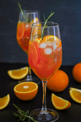 Aperol spritz is a summer drink served in a glass with aperol, prosecco, soda and orange slice. Glasses of icy cocktail in a wine glass at the bar. Black background. Refreshing drinks concept