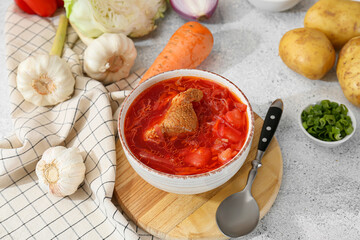Bowl of tasty borscht and ingredients on light background