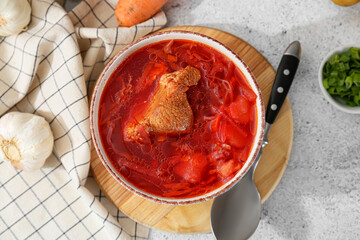 Bowl of tasty borscht and ingredients on light background