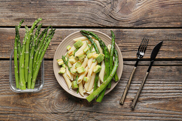 Plate of tasty pasta with asparagus on wooden background