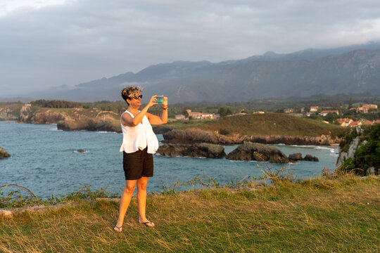 mujer mirando el movil y haciendo fotos en la playa