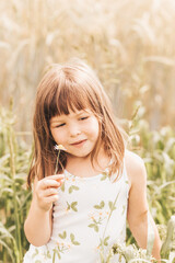 Cute little girl collects flowers on the field in the summer