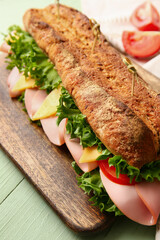 Board with tasty ciabatta sandwich on color wooden background, closeup