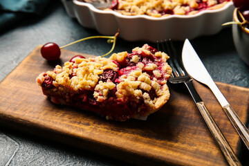 Board with piece of tasty cherry pie on dark background, closeup