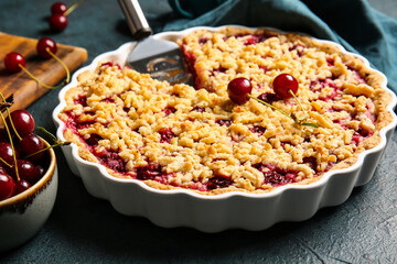 Baking dish with tasty cherry pie on dark background, closeup